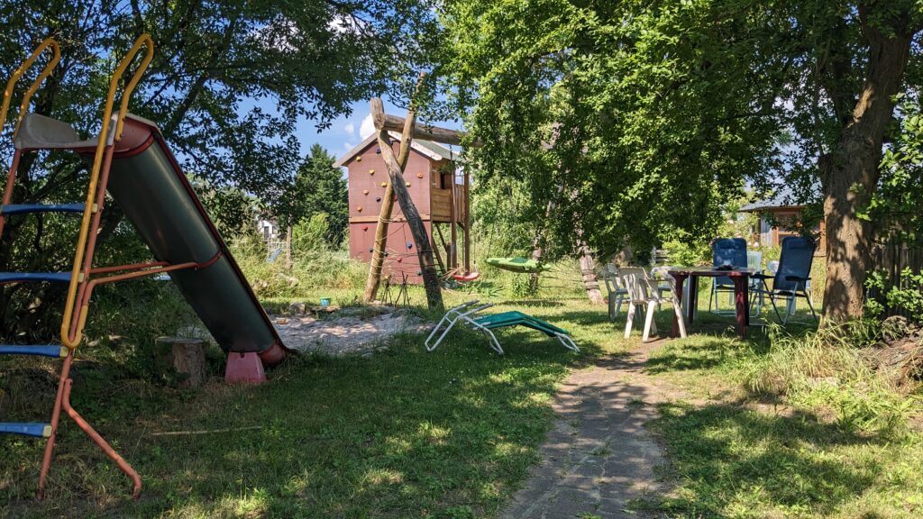 Ein kleiner Garten-Spielplatz: Rutsceh, Sandkasten, Schaukeln und Spielhaus